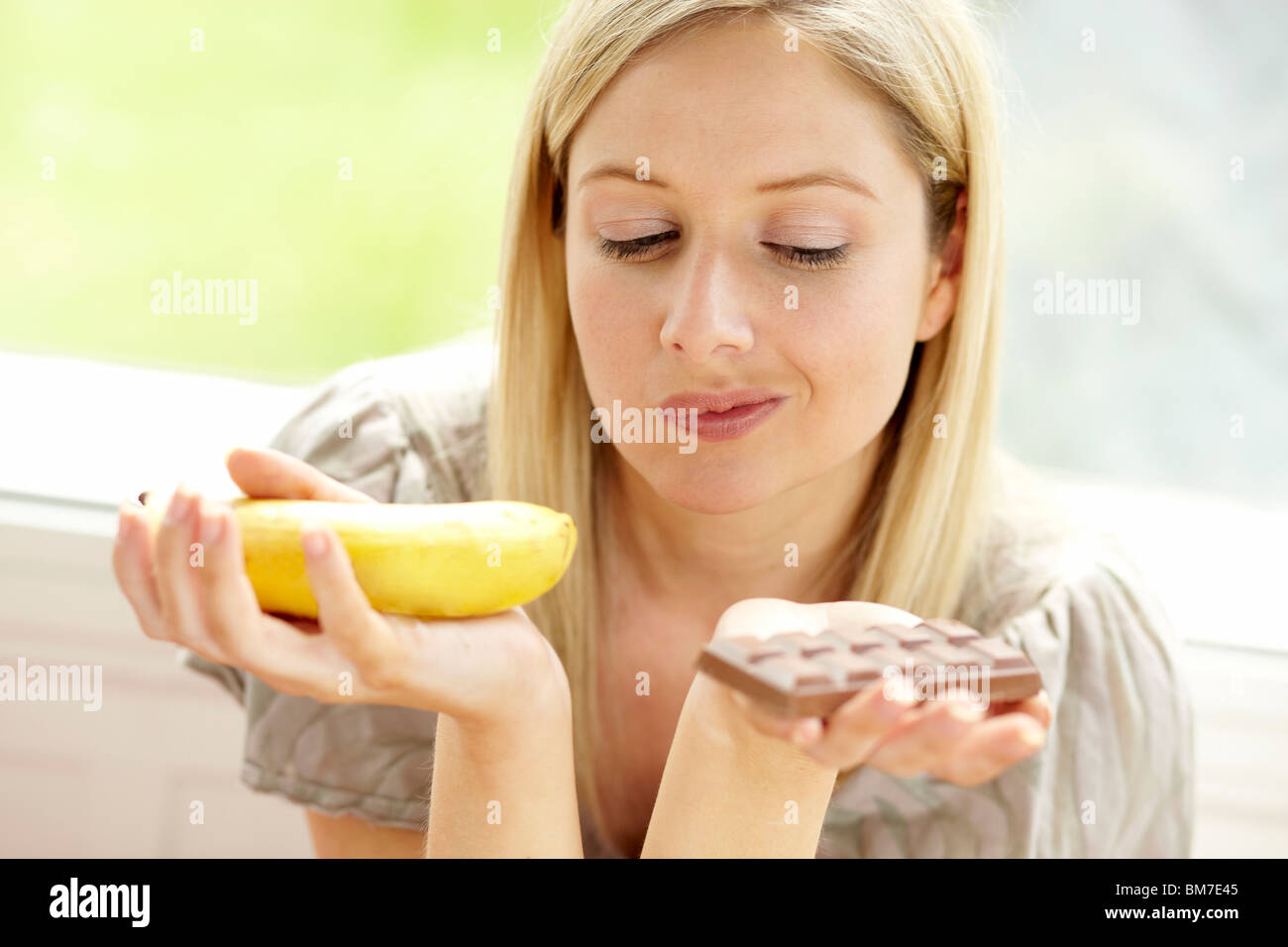 Woman deciding between fruit and chocolate Stock Photo