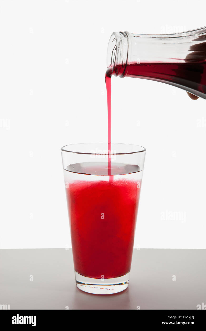 Detail of fruit syrup being poured into a glass of water Stock Photo