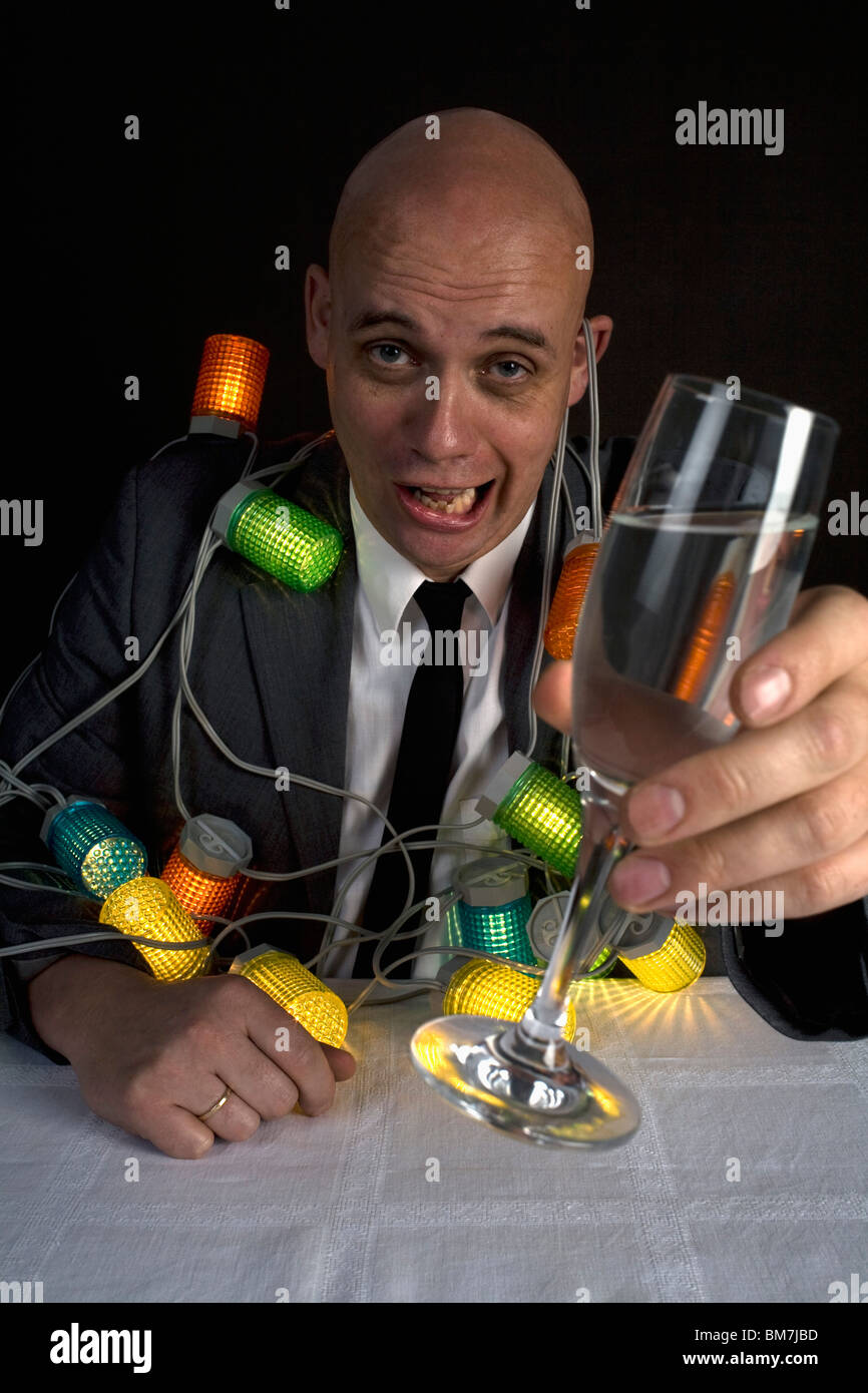 A drunk man with a string of lights around him holding a glass of champagne Stock Photo