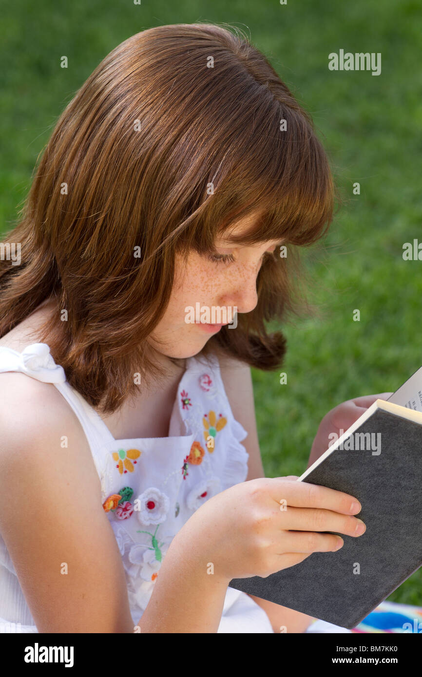 Young beautiful girl reading a book outdoor Stock Photo - Alamy