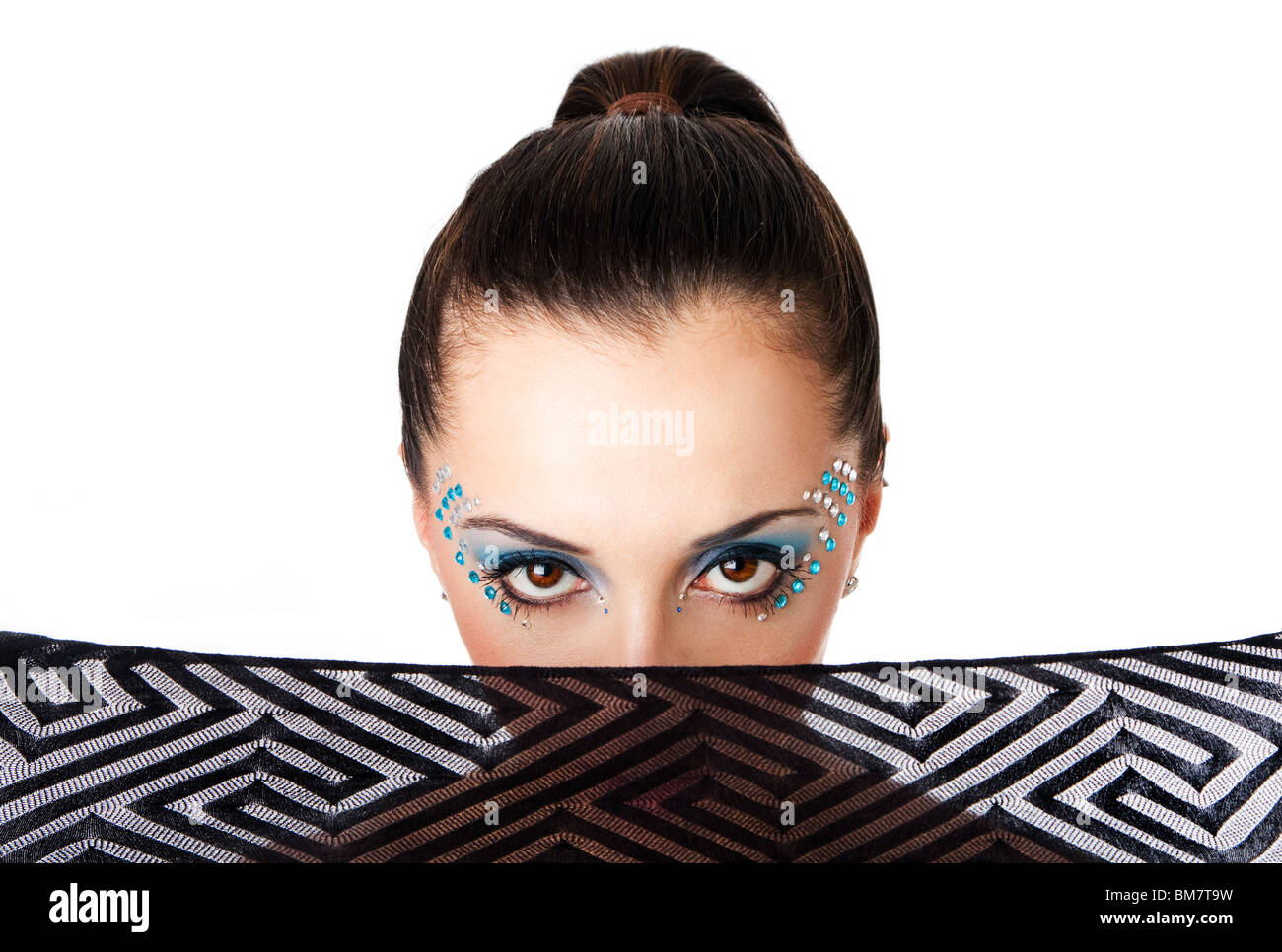 Beautiful female fashion face with blue makeup and gems rhinestones of a Caucasian Hispanic woman with mouth covered with net. Stock Photo