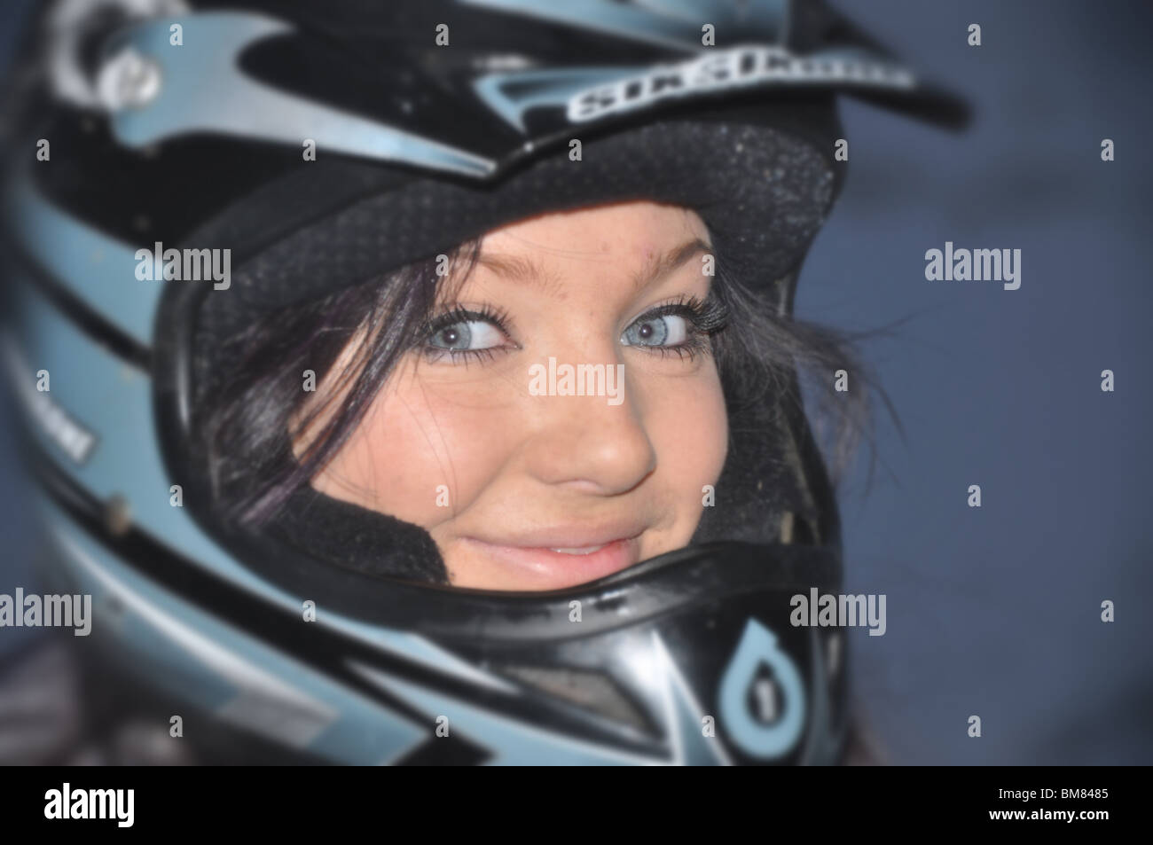 Girl portrait in BMX downhill helmet showing her blue eyes and happy cheeky smile. Stock Photo