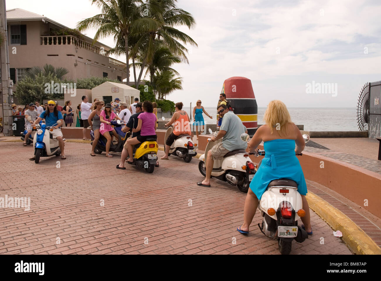 People Ride Scooters at Southernmost Point at Key West Florida USA