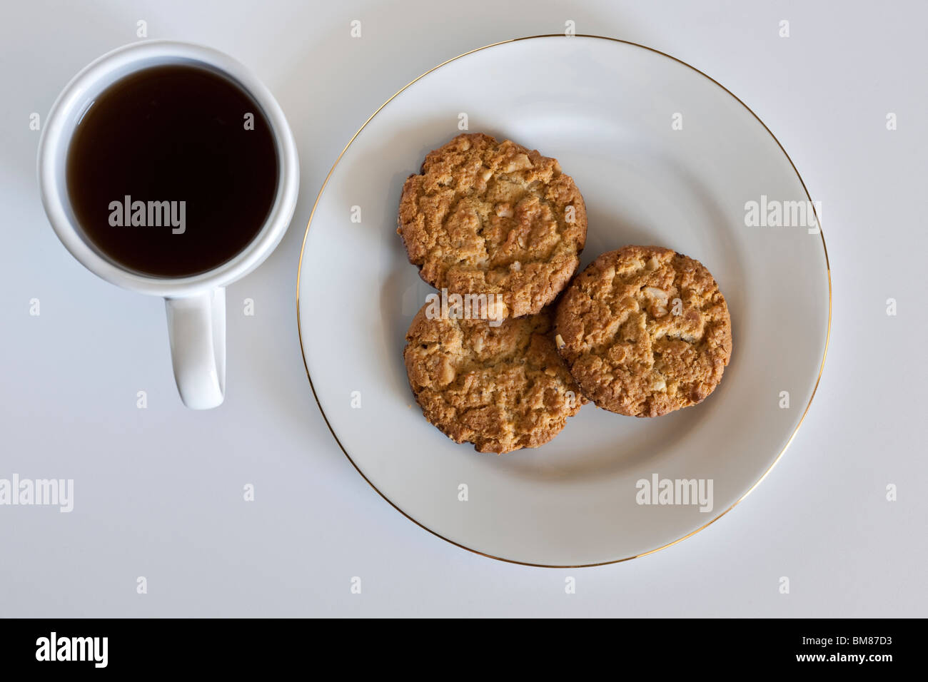 White cup of black coffee and three chocolate crumbly cookies on a white plate Stock Photo