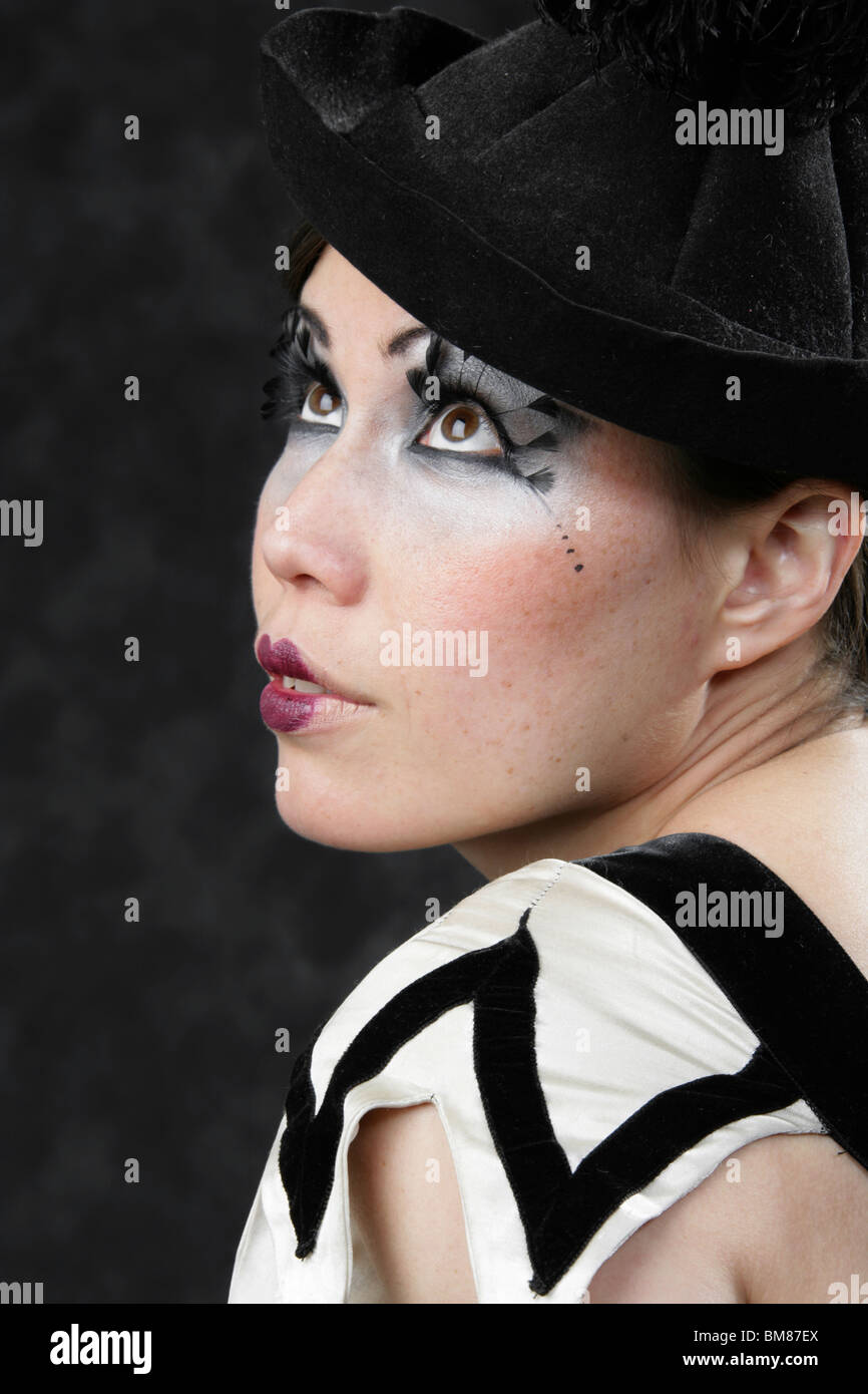 Young Woman Dressed in a Black and White Clown Outfit and Black Hat with Feather Eyelashes Stock Photo