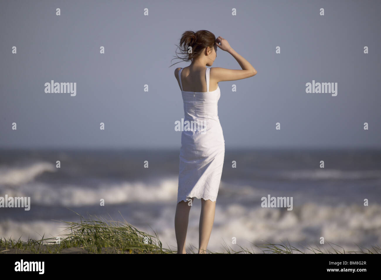 Young woman standing on beach Stock Photo - Alamy