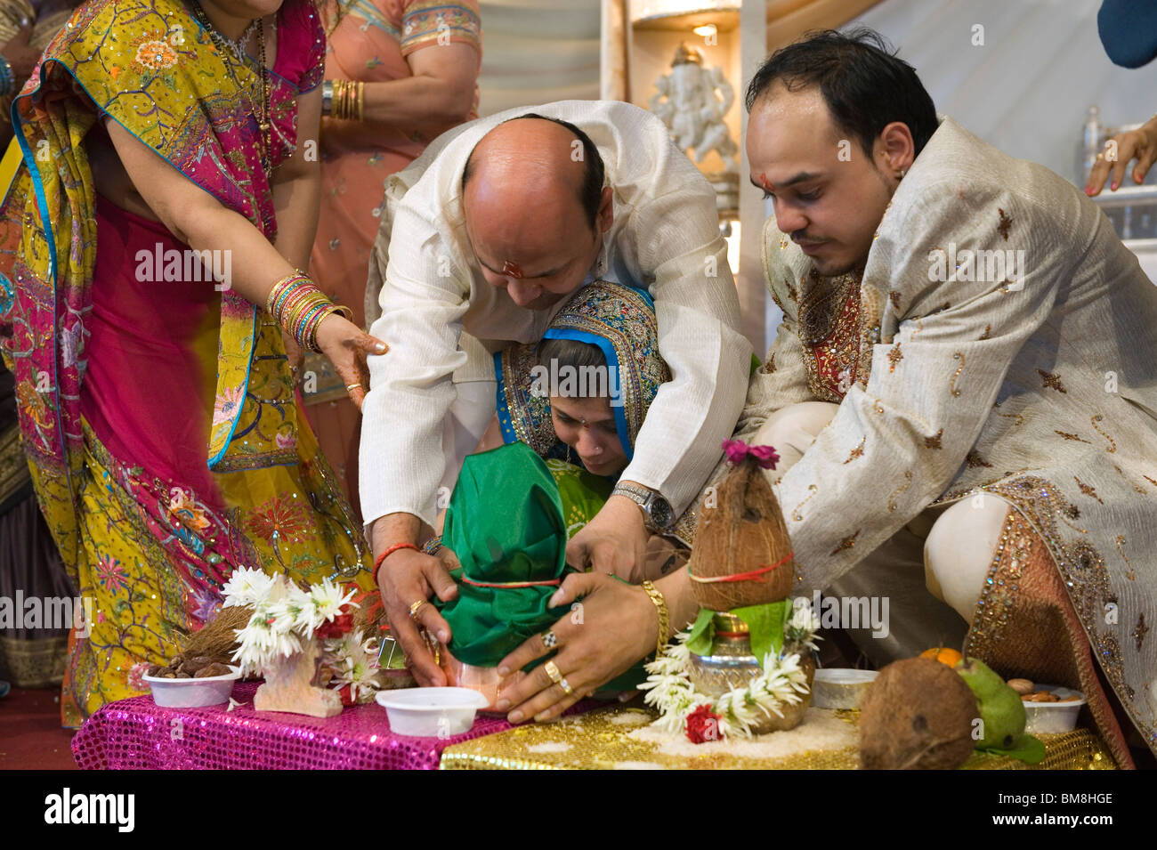 Hindu Wedding, West London held at the Navnat Centre,Hayes, Middlesex. Bride with Father and brother lay the water . Stock Photo
