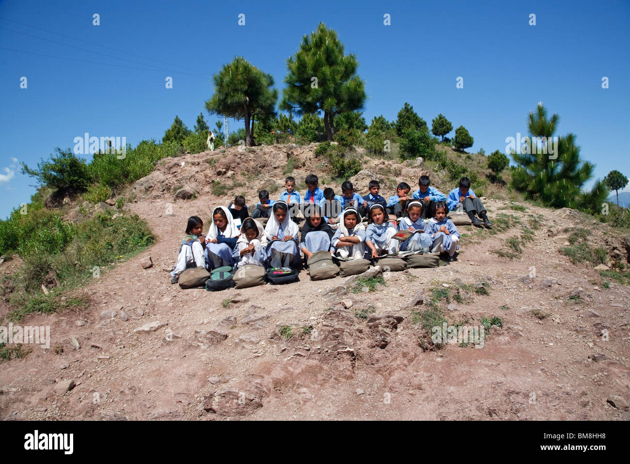 Young students during a lesson outside their school in the mountains of Kashmir near Muzzafarabad, Pakistan. Stock Photo