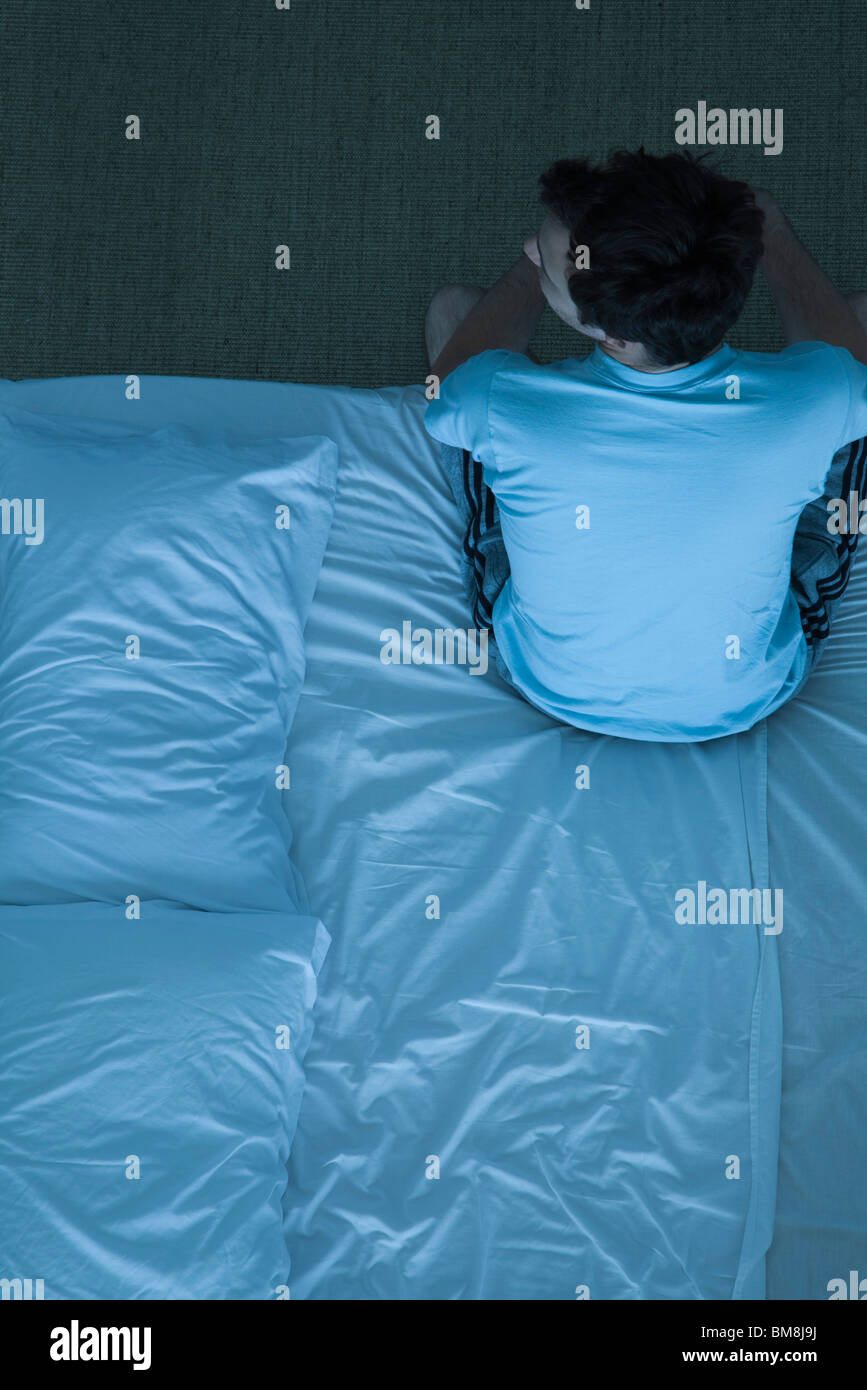 Man sitting on bed unable to sleep Stock Photo - Alamy