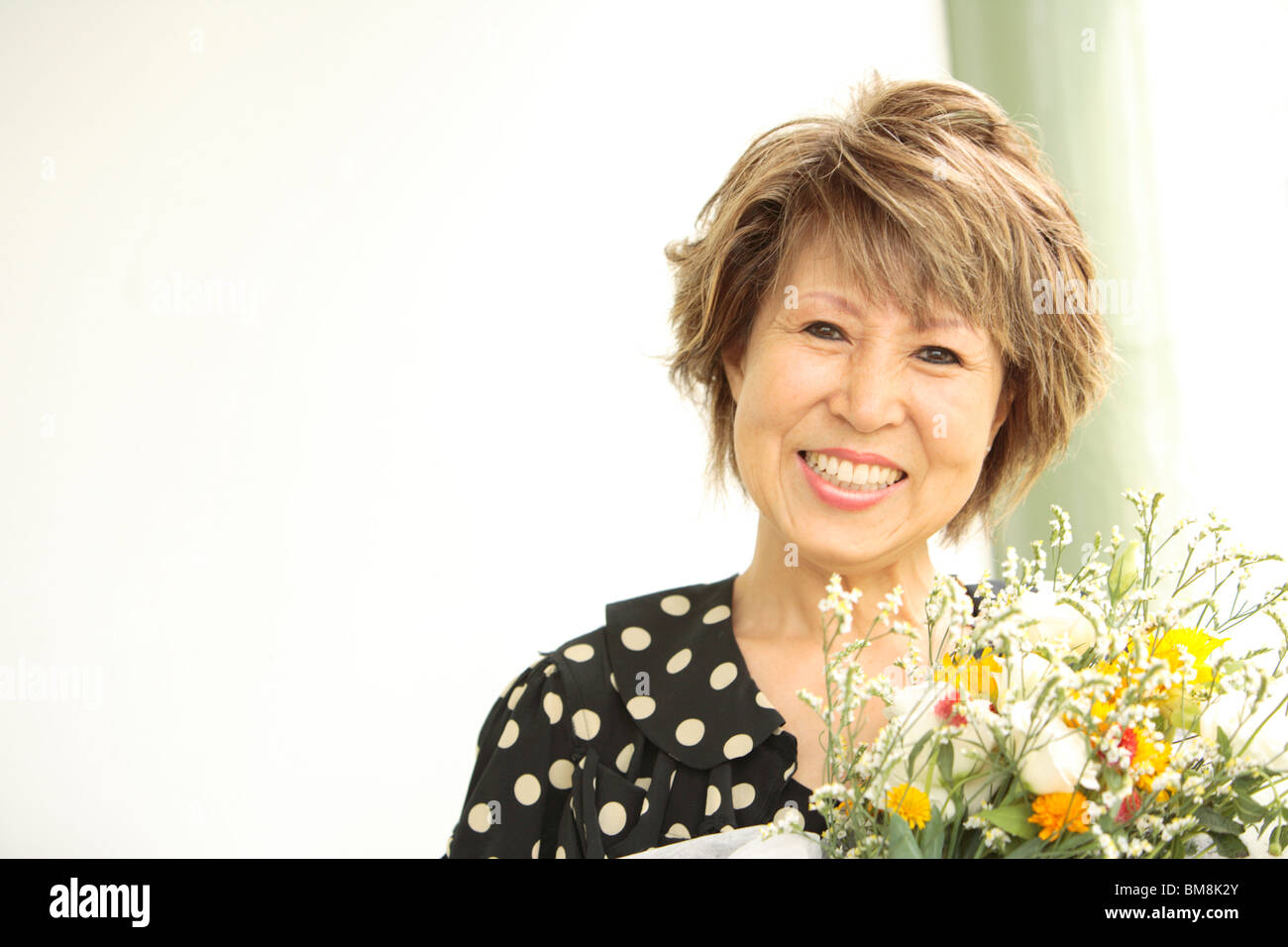 Portrait of mature woman holding flower bouquet, smiling Stock Photo ...