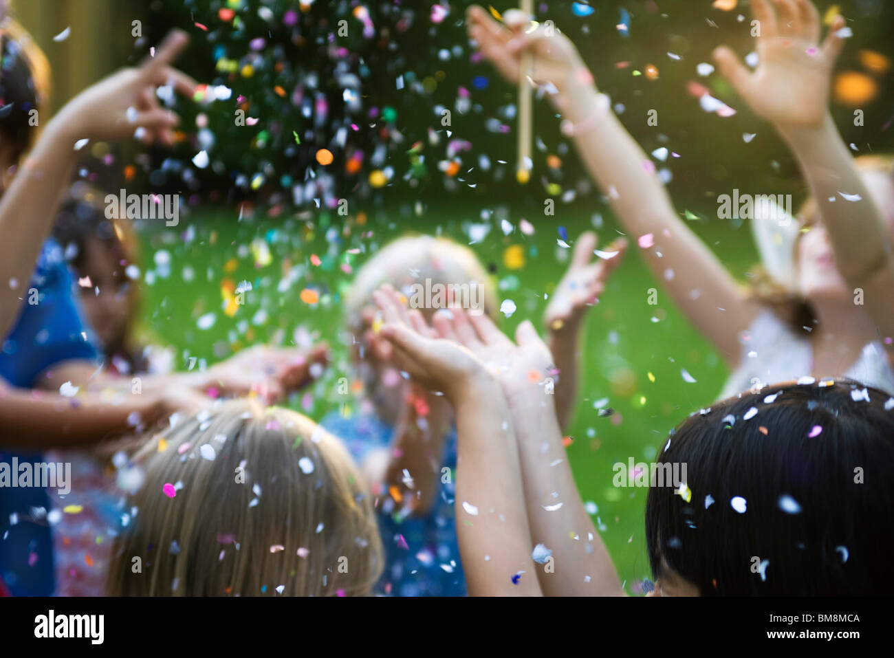 Children showered in falling confetti Stock Photo