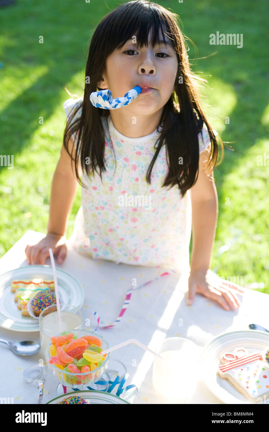 Girl at party enthusiastically blowing party horn blower Stock Photo ...