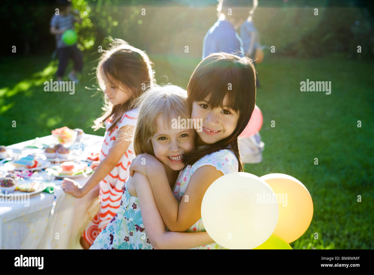 Young friends embracing at outdoor party, portrait Stock Photo