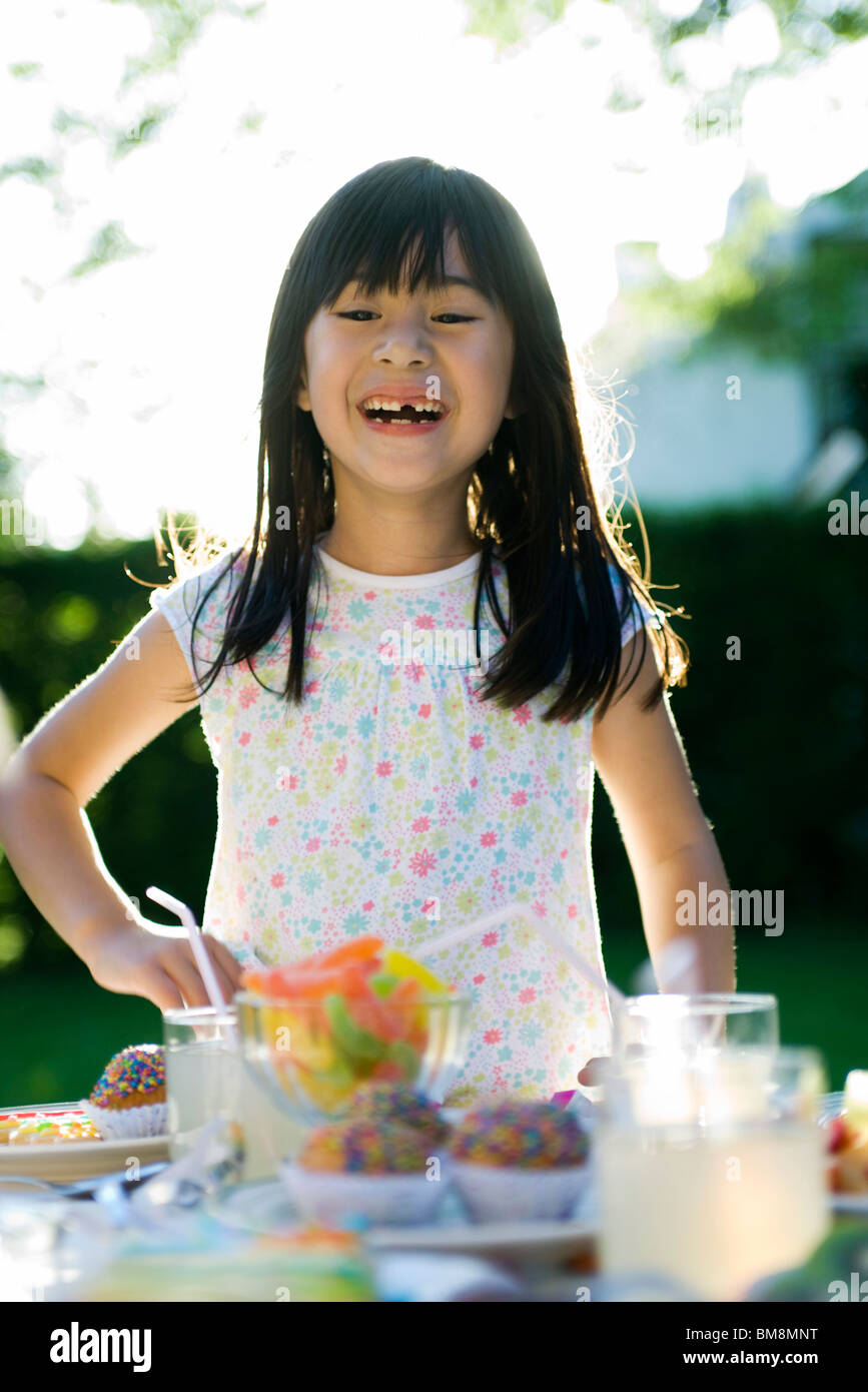 Girl at party admiring sweets placed on table Stock Photo