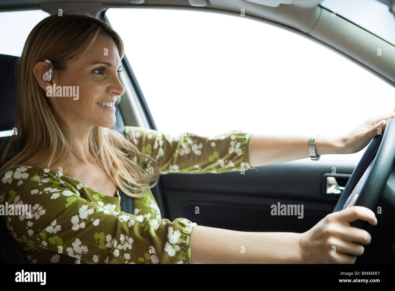 Driving while using hands free bluetooth earpiece Stock Photo Alamy