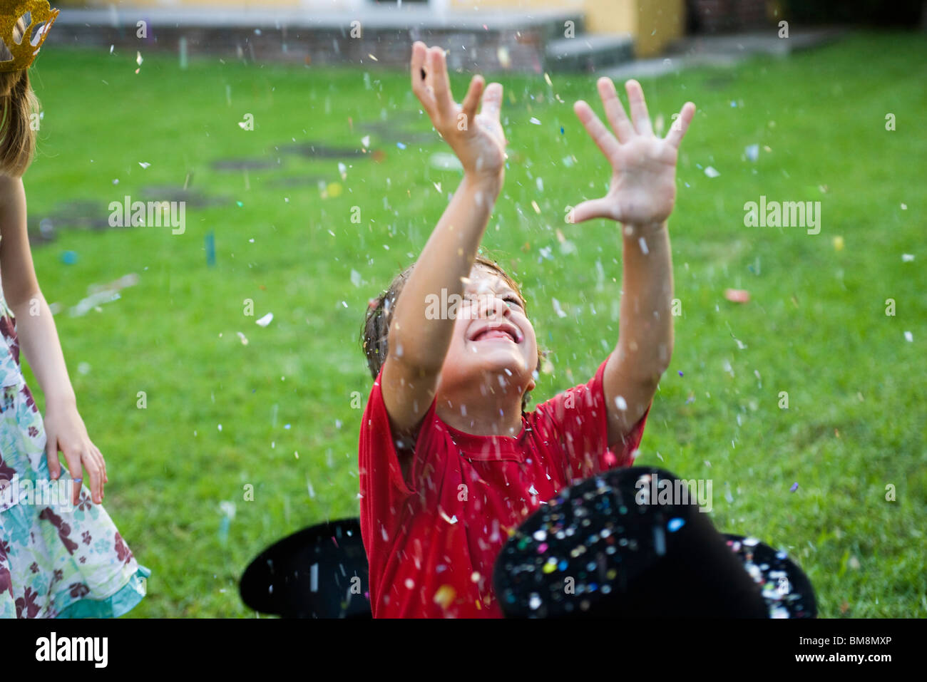 Boy with arms raised showered in falling confetti Stock Photo - Alamy