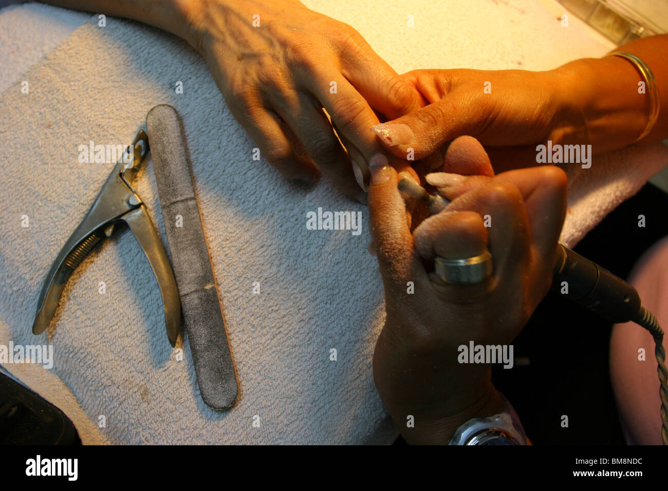 Manicurist takes care of womans fingernails, filing and smoothing after