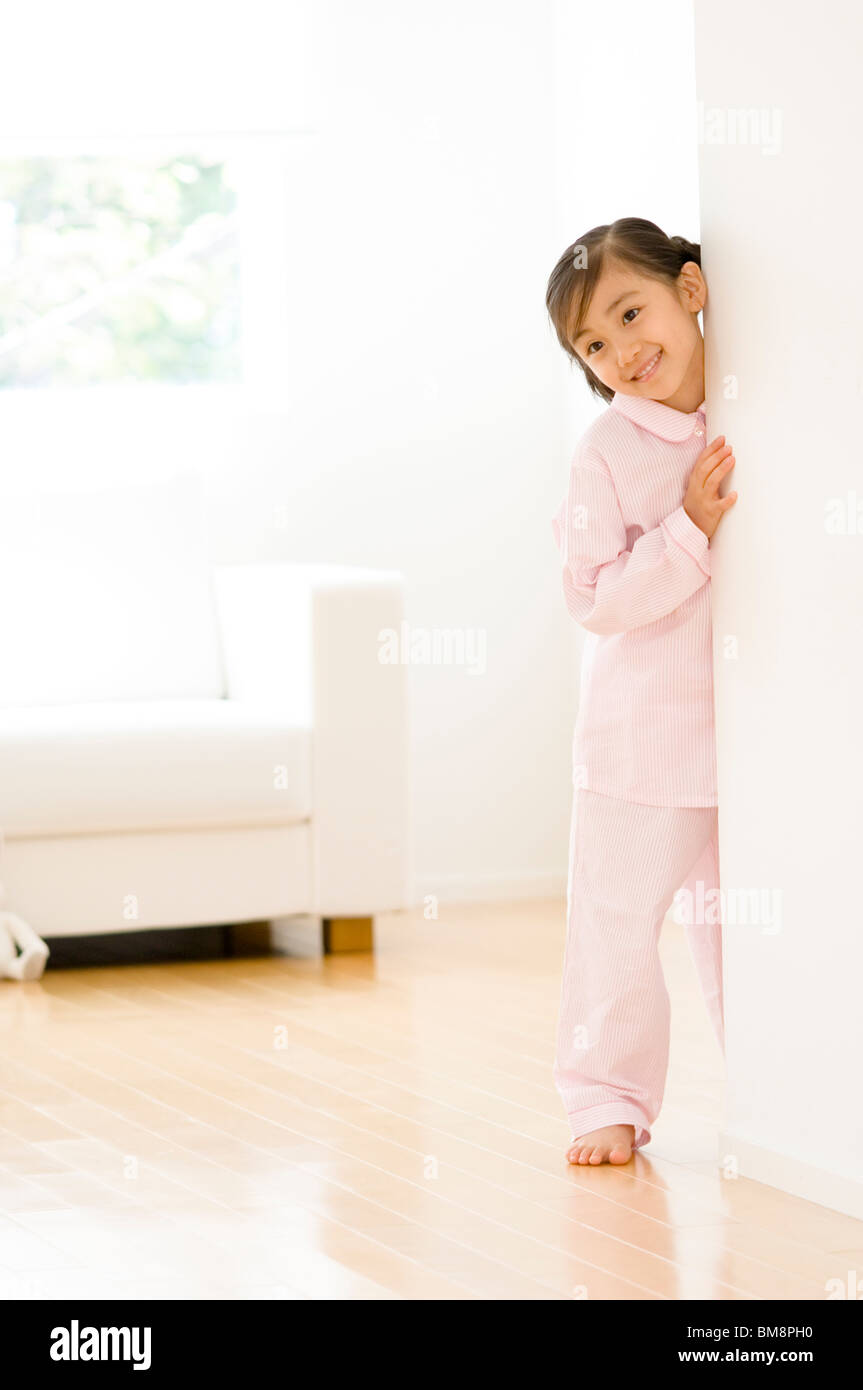 Girl in pajamas standing next to wall Stock Photo