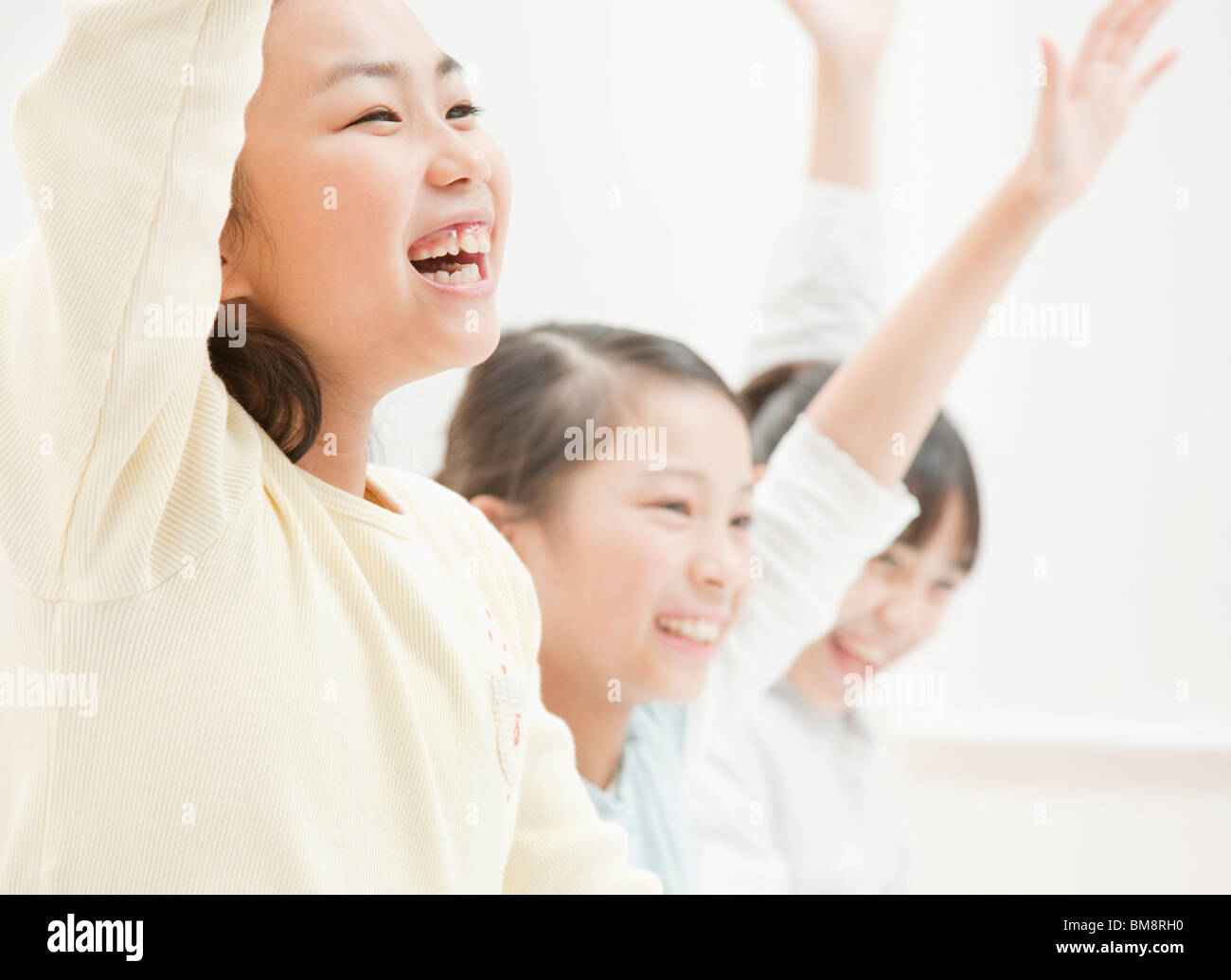 Girls Studying at Desk, Putting Their Hands Up Stock Photo