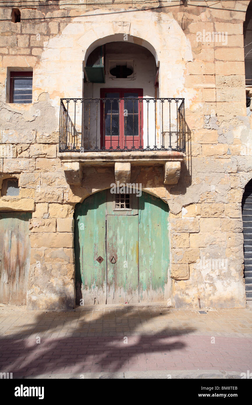 St Lawrenz, Gozo, Malta. An old green door below a traditional Maltese balcony. Date stone with cross, 1806 Stock Photo