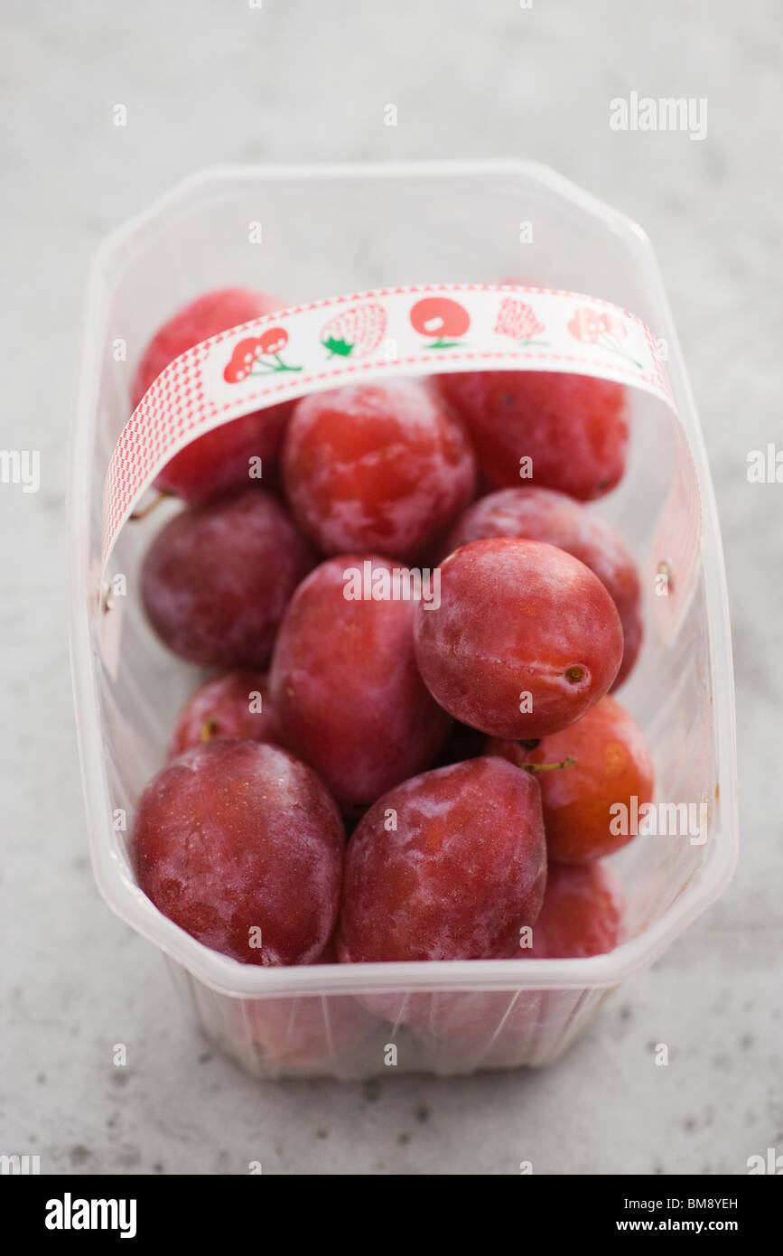 Plums in plastic container Stock Photo