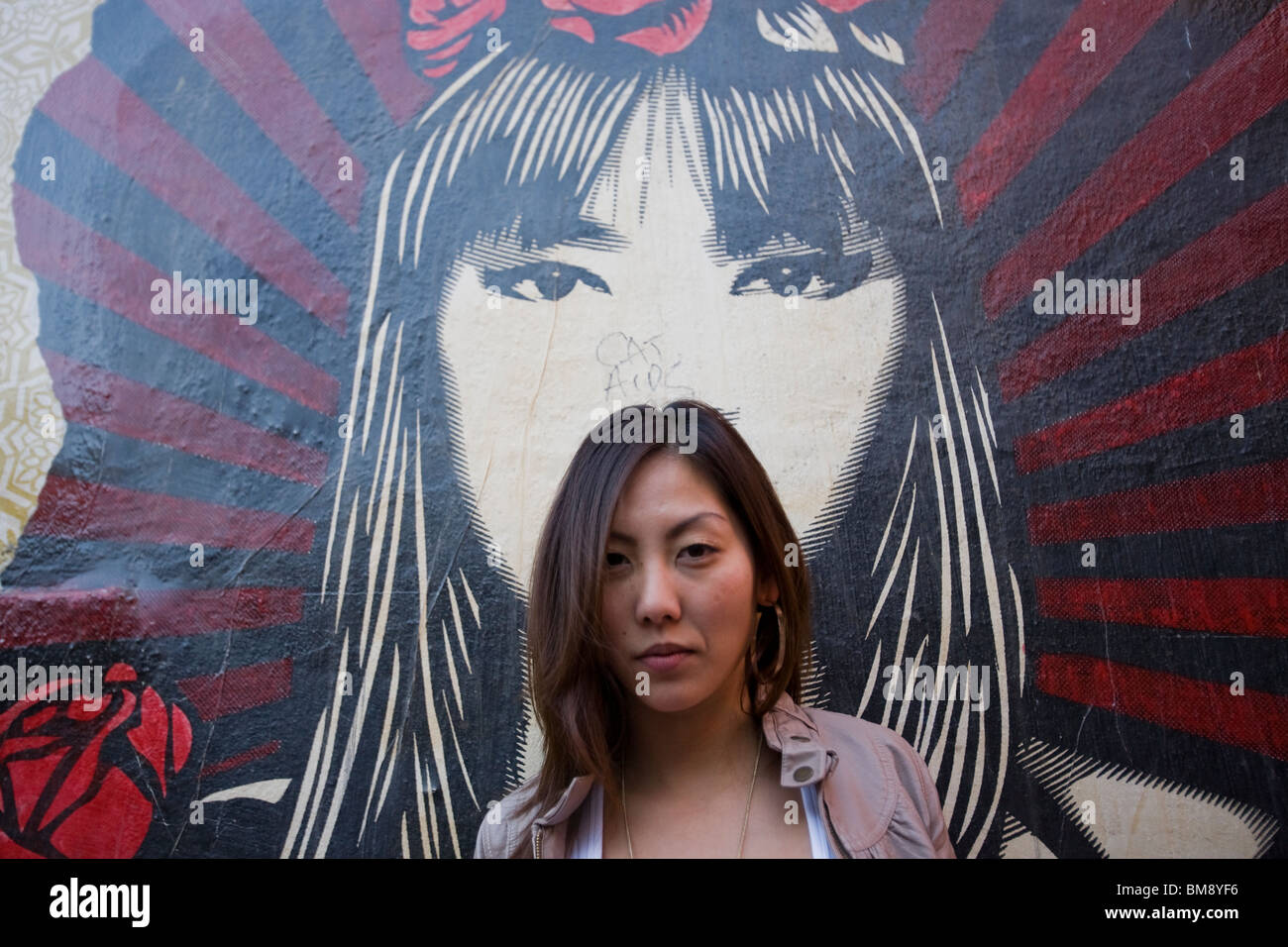 Asian female in front of wall art of Asian girl Stock Photo