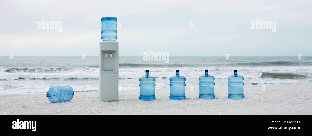 Water cooler and water jugs lined up on beach Stock Photo Alamy