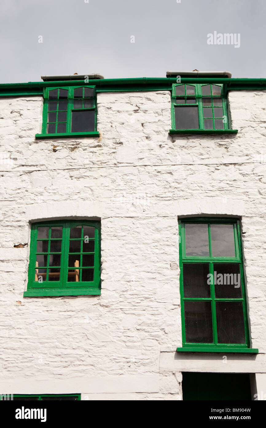 UK, Cornwall, Launceston, Madford Lane, green painted windows set in whitewashed stone house wall Stock Photo