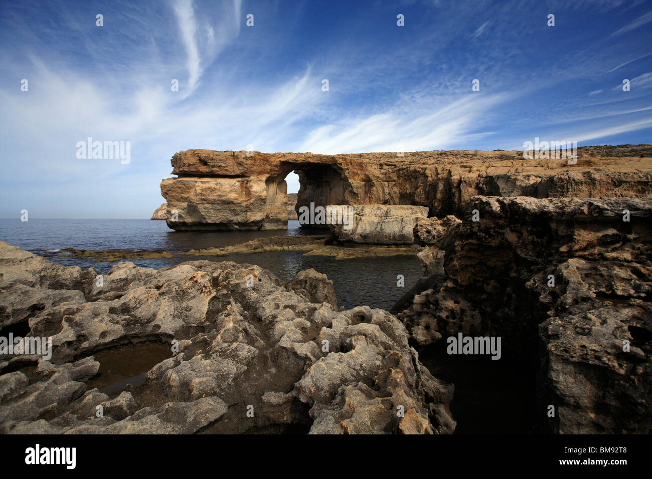 A blue sky with streaky white clouds behind the Azure window, a limestone feature on the west coast of Gozo Stock Photo