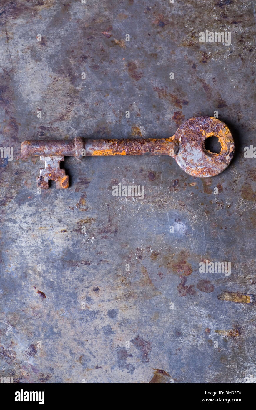 Dirty old rusted house key over a grunge background Stock Photo