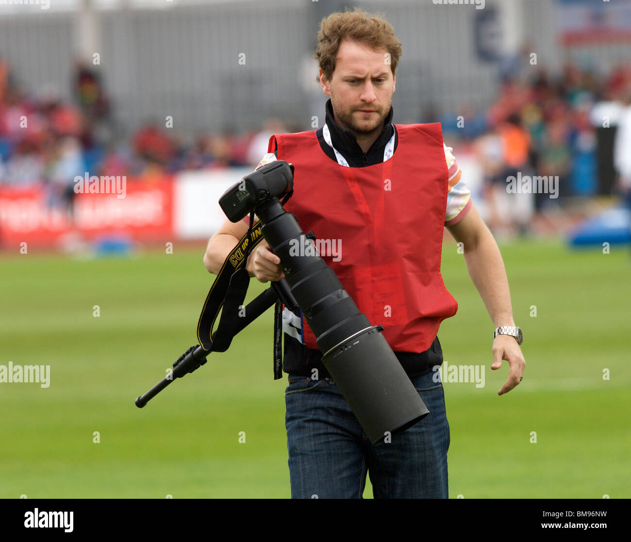 sports photographer carrying a nikon d3 and telephoto lens at sportcity manchester Stock Photo
