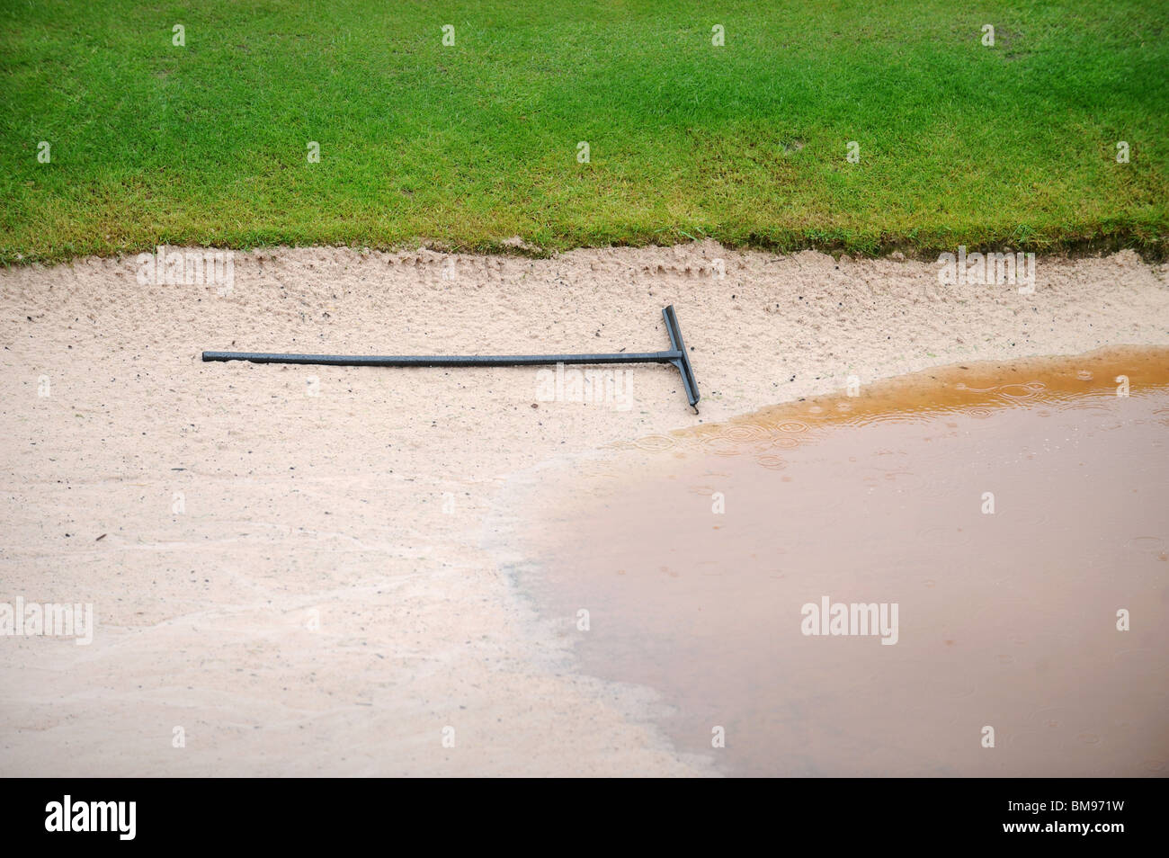 A rake in a waterlogged bunker during a downpour at the Celtic Manor