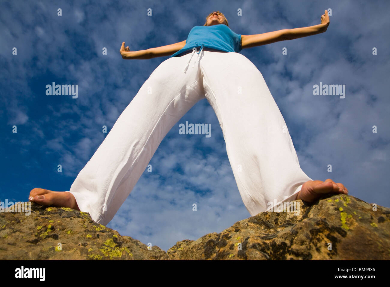 Woman Doing Yoga Against A Blue Sky Low Angle Shot Stock Photo