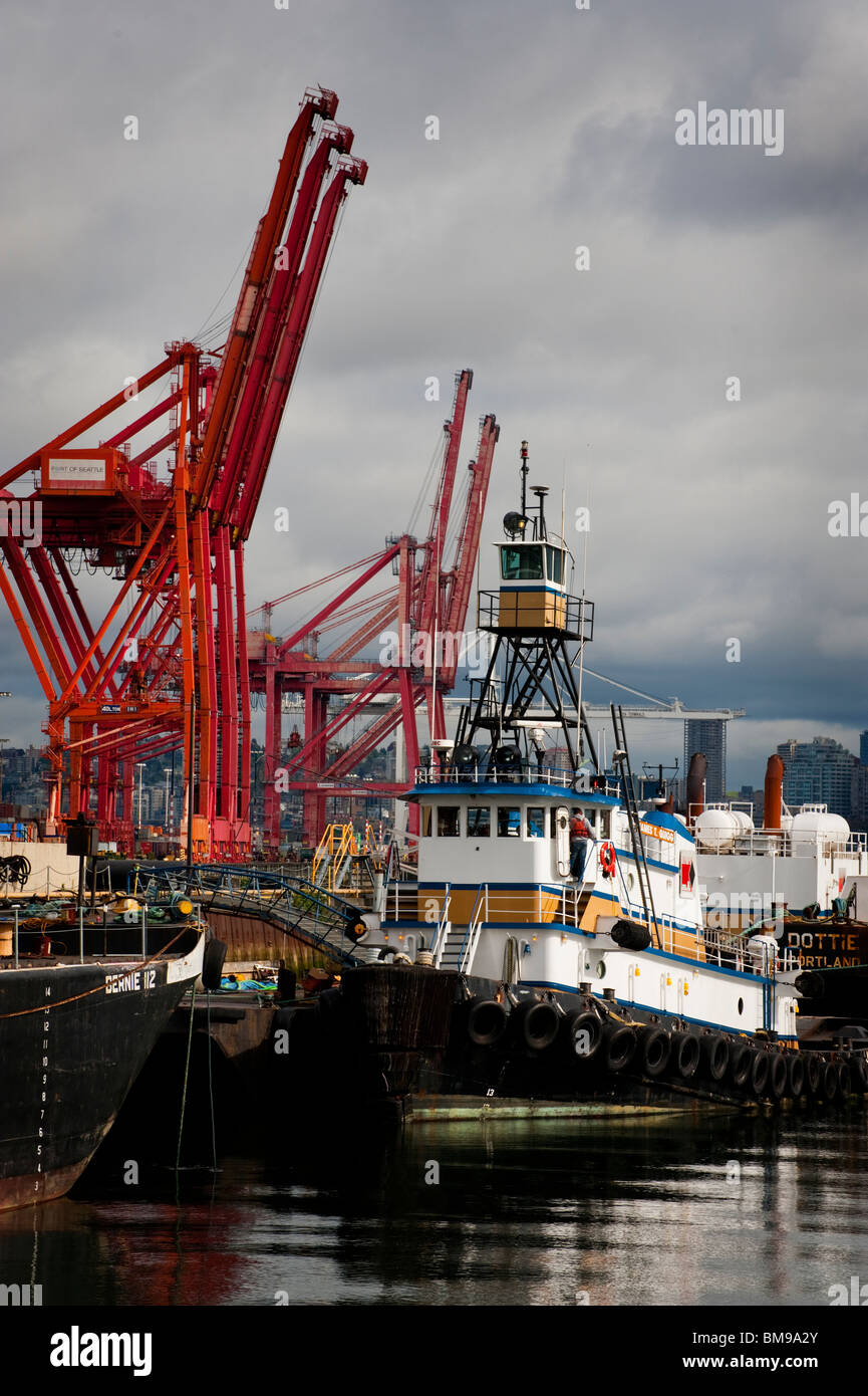 A tug boat stands ready to guide a huge container ship into the Port of ...