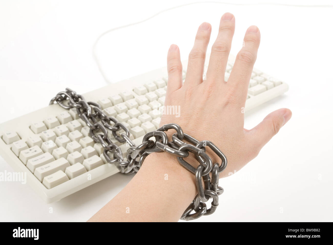 Hand had been Tied Up by chain with Computer Keyboard Stock Photo