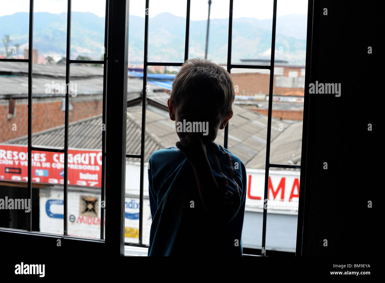 Silhouette of boy 4 years standing by window in down town building. Stock Photo