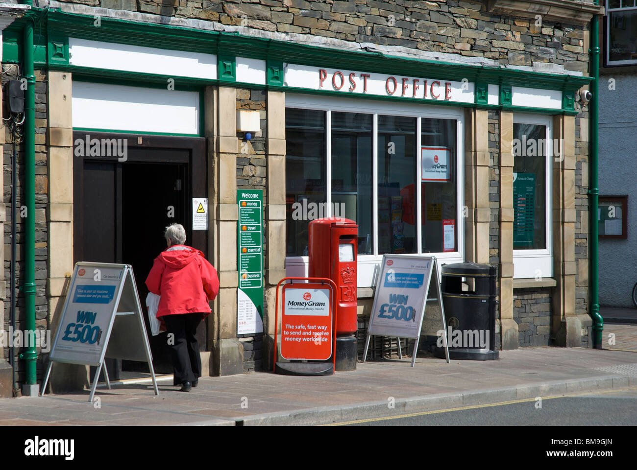 Woman walking into post office, Windermere, Lake District National Park
