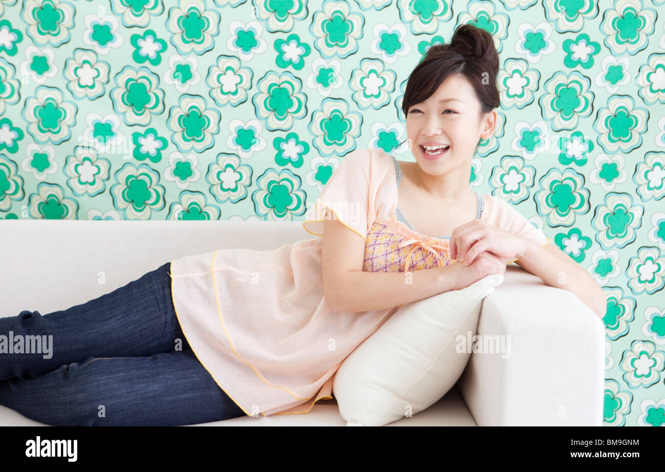 Young woman lying on a couch Stock Photo - Alamy