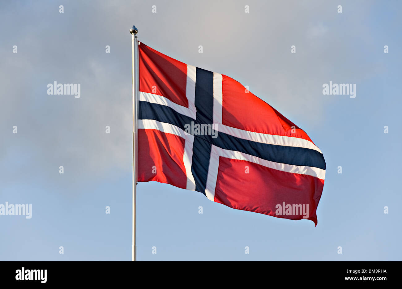 Norwegian Flag Flies Proudly in a Breeze from a Flagpole in a Clear Blue Sky Stock Photo