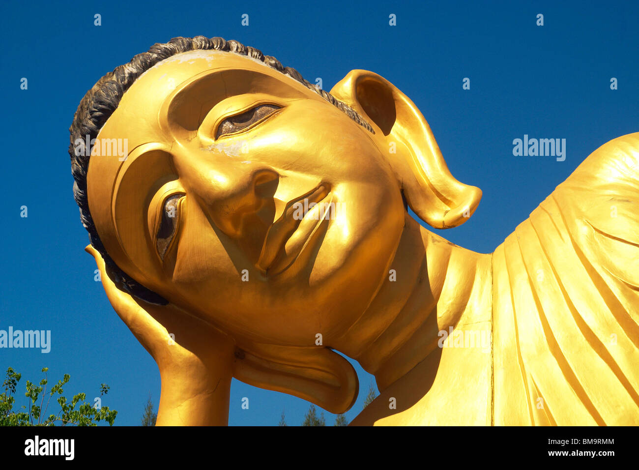 Head of a large gold reclining Buddha at Wat Sri Sunthon, a Buddhist temple on the island of Phuket Stock Photo