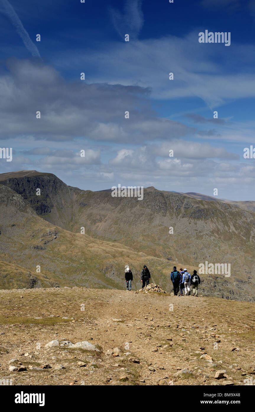Walkers on the North West edge of Fairfield Summit with the Hellvelyn range in the distance Stock Photo
