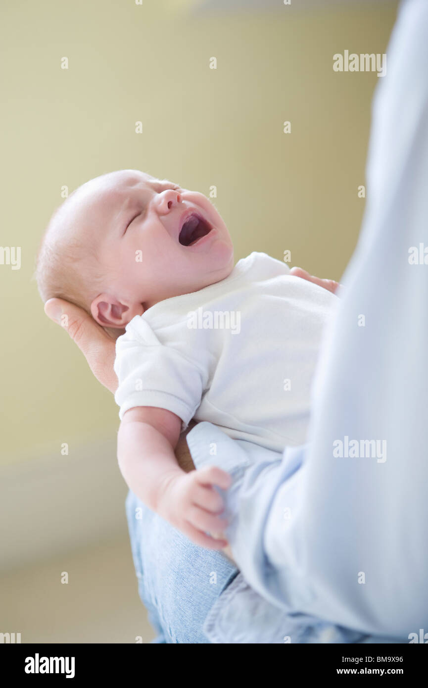Man holds crying two week old newborn baby Stock Photo