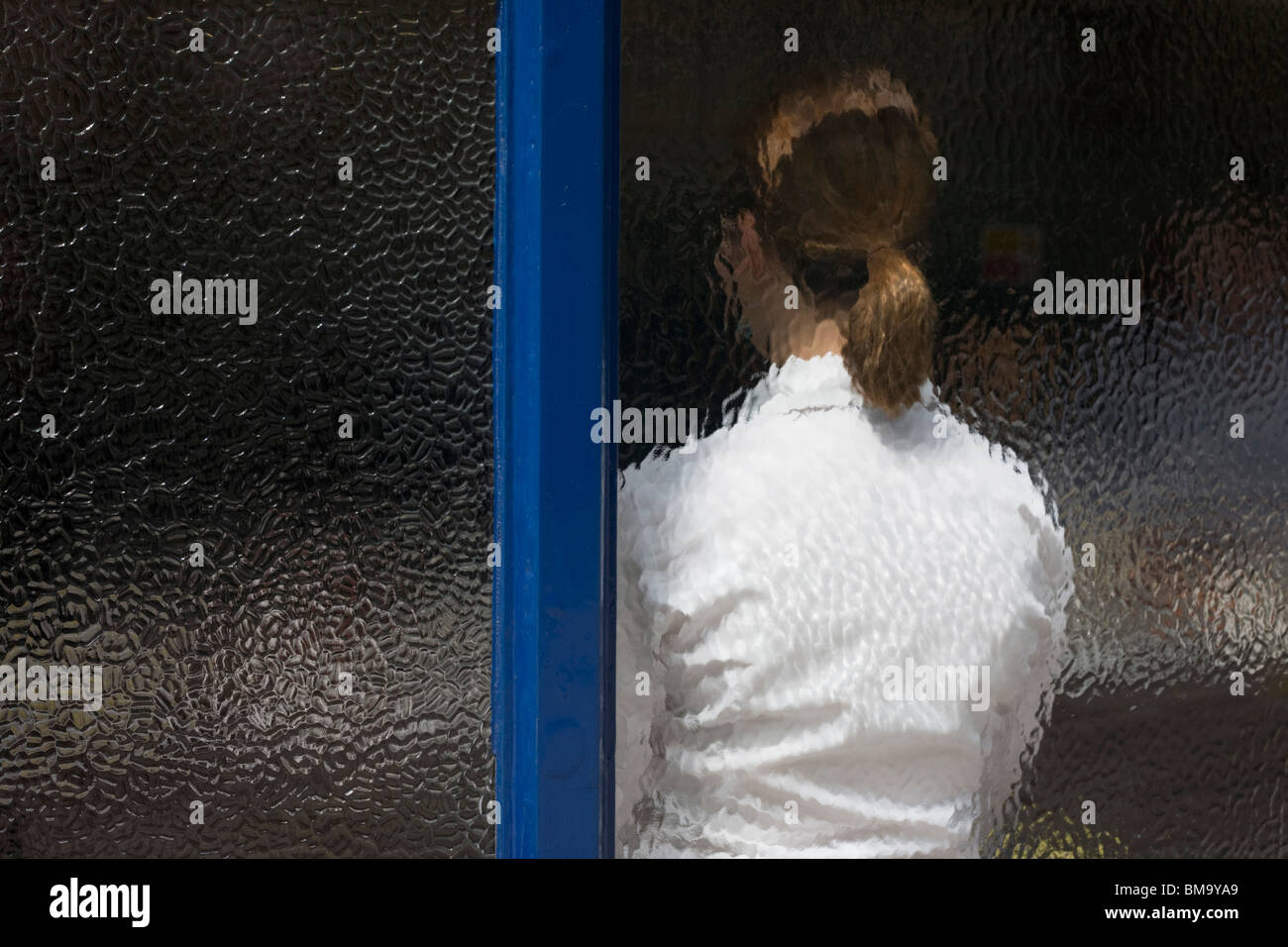 A lady waitress awaits lunchtime business, seen through the frosted window of Sweetings seafood restaurant, City of London. Stock Photo