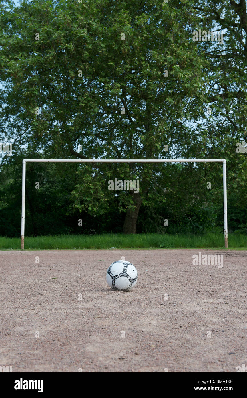 Football and goal on dirt pitch Stock Photo