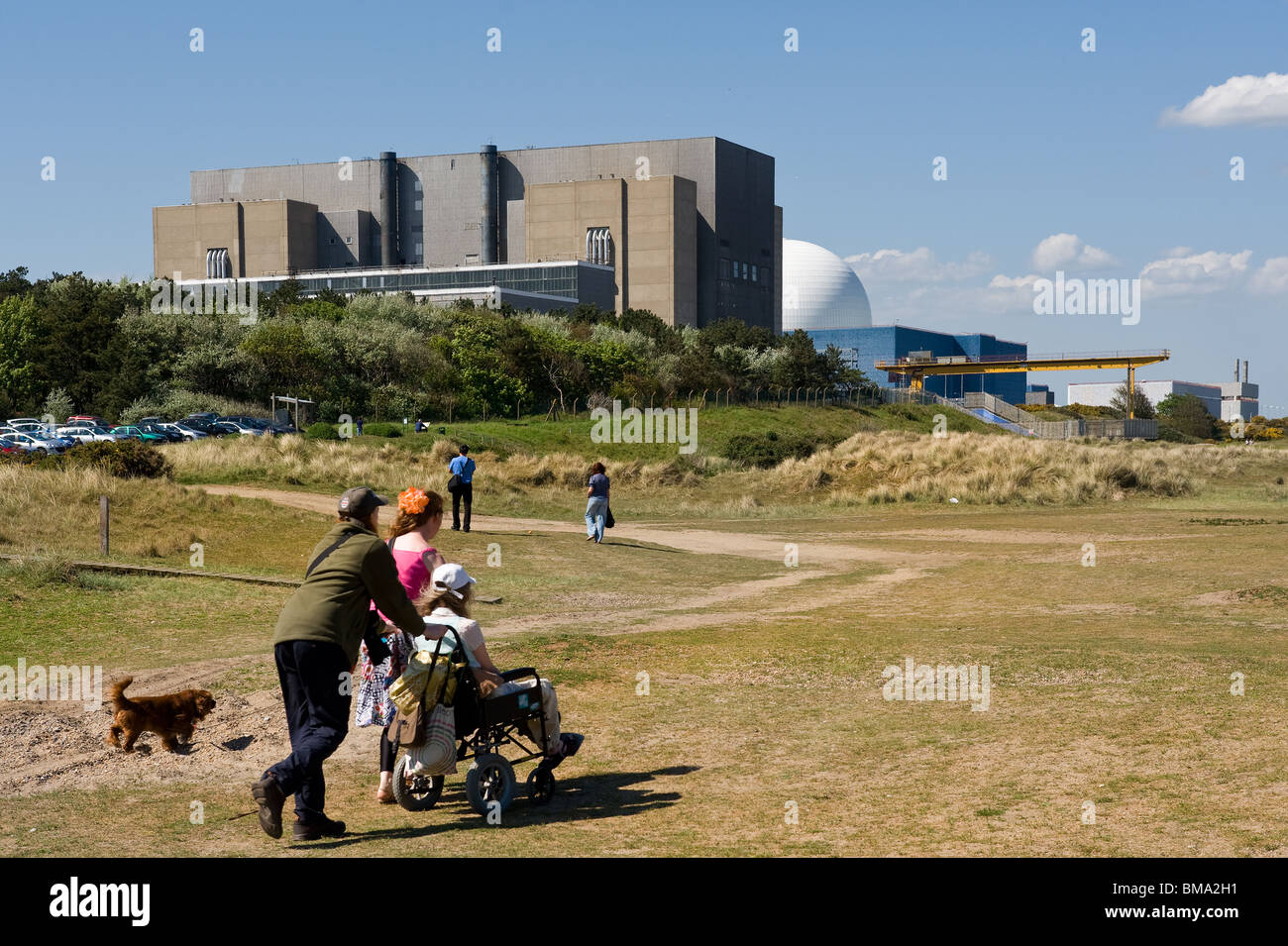 A woman in a wheelchair being pushed along Sizewell Beach in Suffolk. Stock Photo