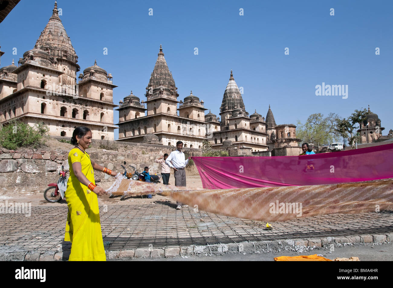 Indian people drying saris after bathing in the Petwa river. On the background the Royal Cenotaphs. Orchha. India Stock Photo