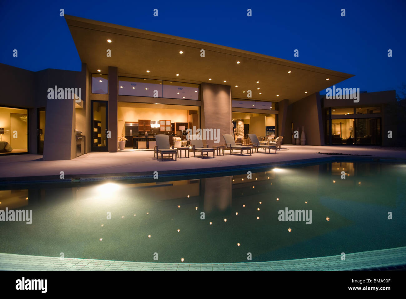 Lit swimming pool and house exterior at night Stock Photo
