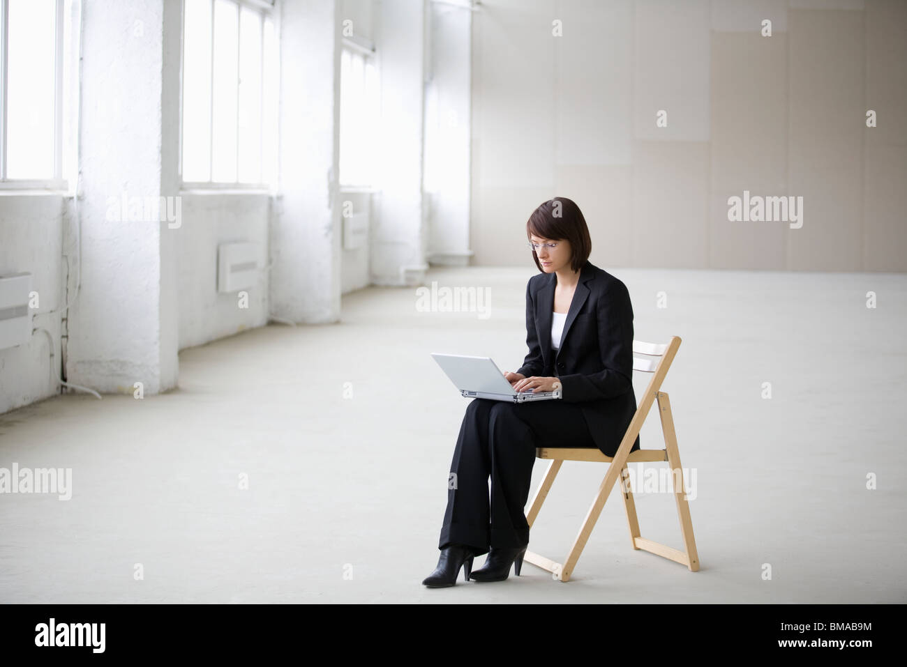 Business woman works on laptop in empty warehouse Stock Photo