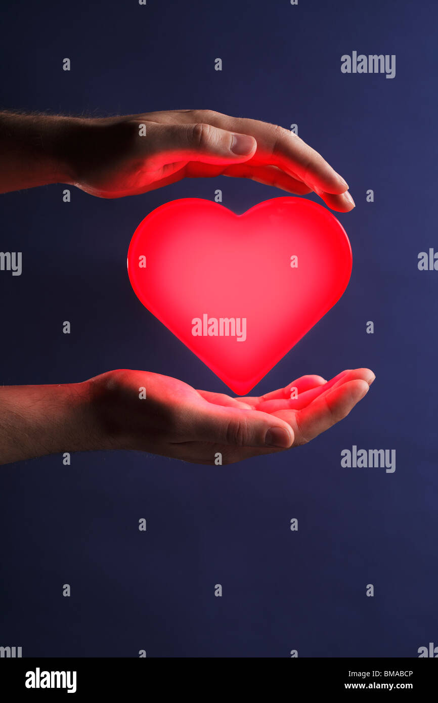 Man holding a glowing red heart in his hands Stock Photo - Alamy