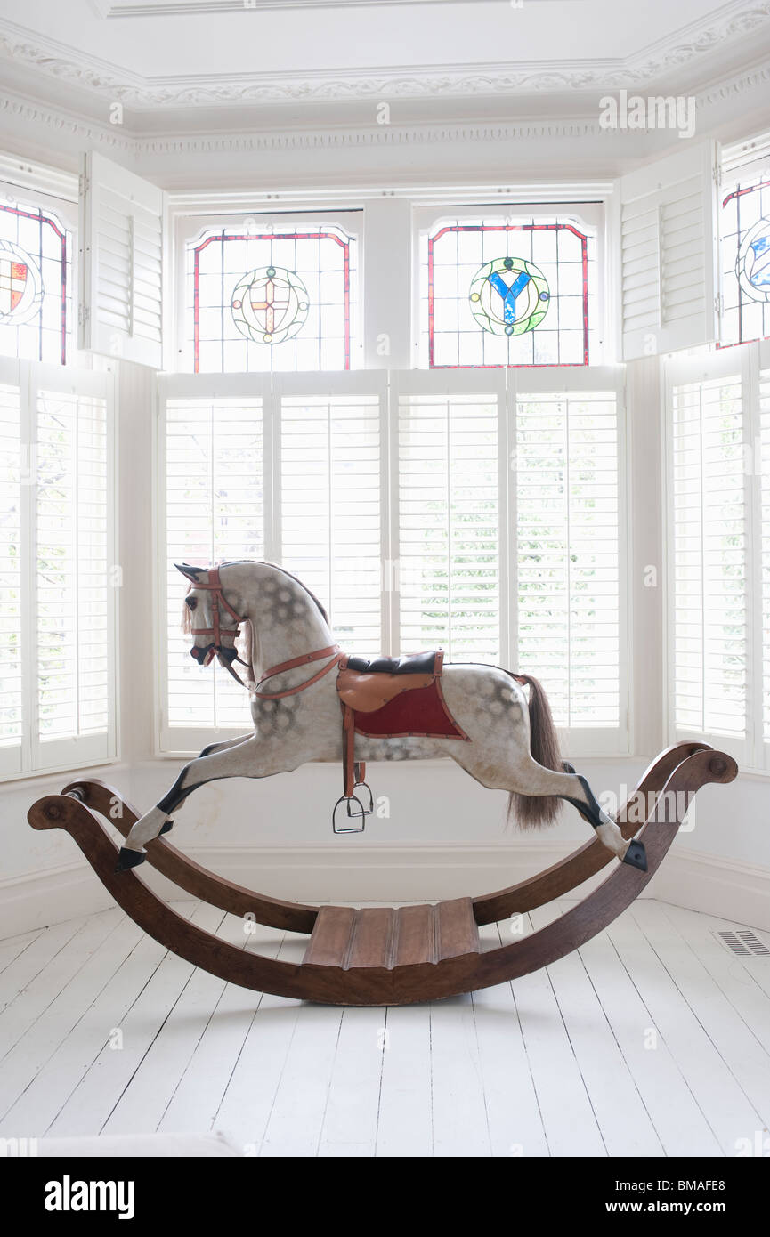 Antique rocking horse in bay window with stained glass, London Stock Photo